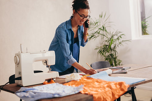 Woman tailor receiving an order of masks on phone