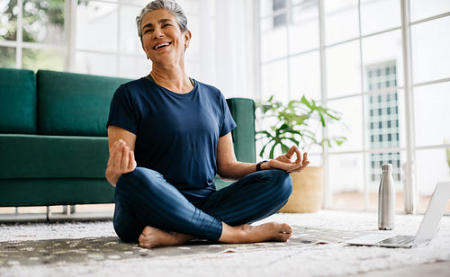 Yoga happiness: Senior woman smiling as she practices meditation at home