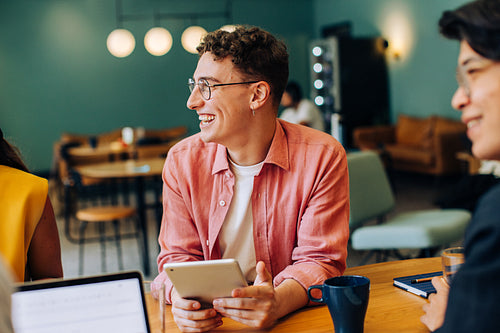 Smiling colleagues discuss ideas during a cheerful meeting in a trendy cafe