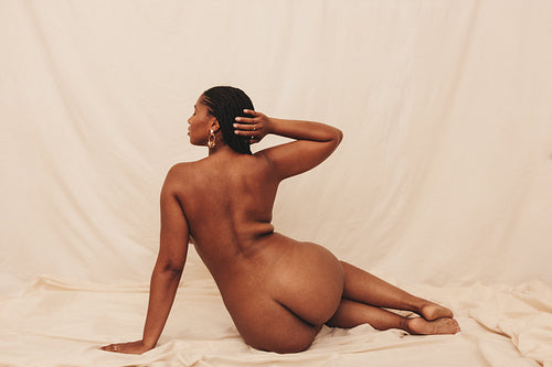 Curvy young woman posing nude in a studio