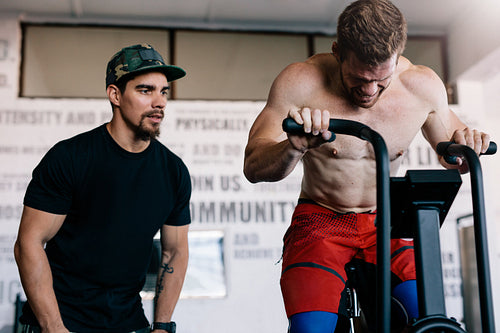 Fitness instructor with man workout on exercise bike