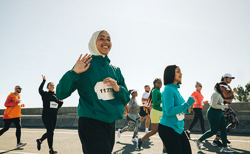 Smiling muslim female runner waving during marathon event