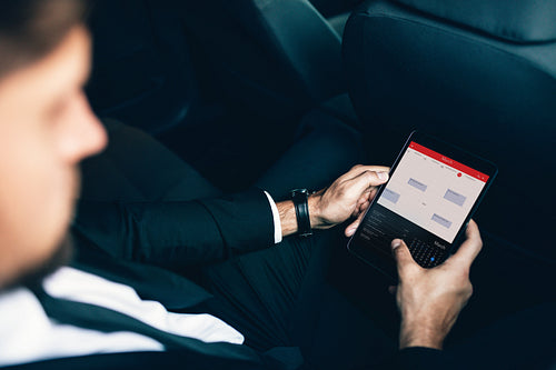 Businessman sitting in car scheduling meetings on smartphone