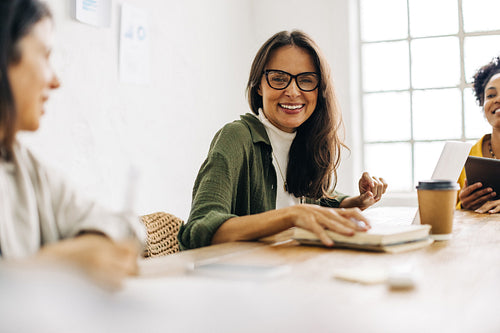 Business woman smiling at the camera during a team meeting in a boardroom