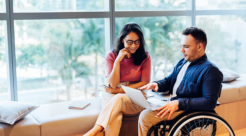 Two colleagues collaborate on laptop in wheelchair today