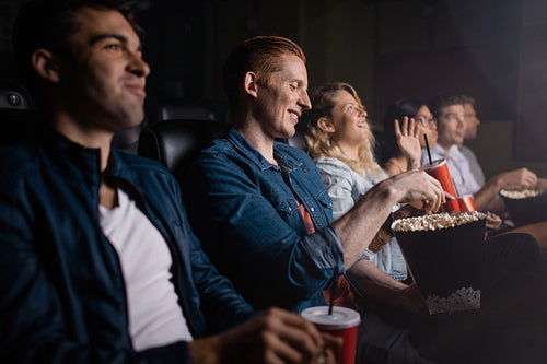 Young man with friends watching movie in cinema