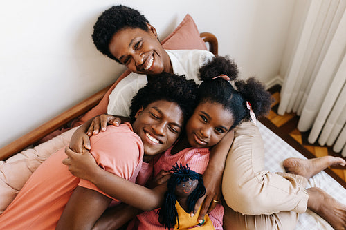 Happy mother cuddling her two children on the bed