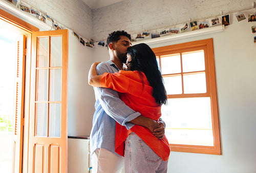 A young couple embracing in a bright and cozy apartment interior