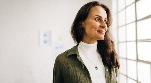 Confident female entrepreneur looking outside her window in an office