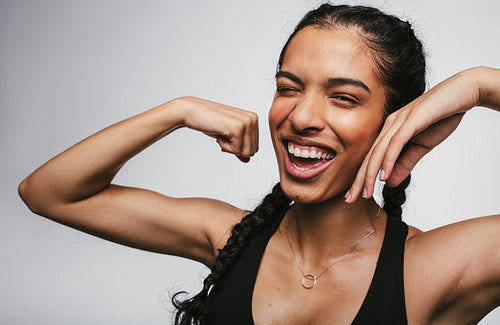 Cheerful fitness woman showing biceps