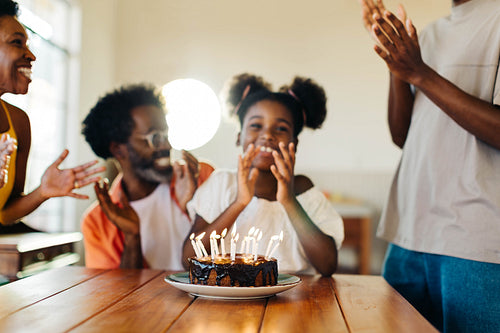 Family celebrating birthday with cake and gifts