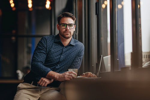 Businessman sitting in a cafe with laptop and food