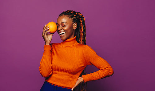 Happy woman holding fresh citrus fruit on a colorful background