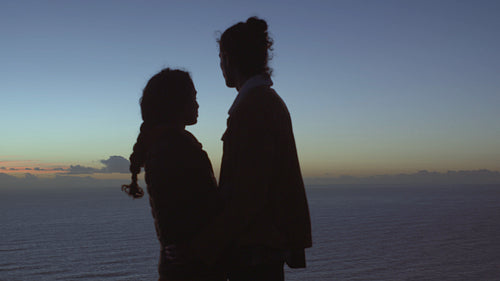 Romantic couple embracing on hill top at dusk