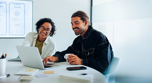 Two ux designers share a laugh over laptop
