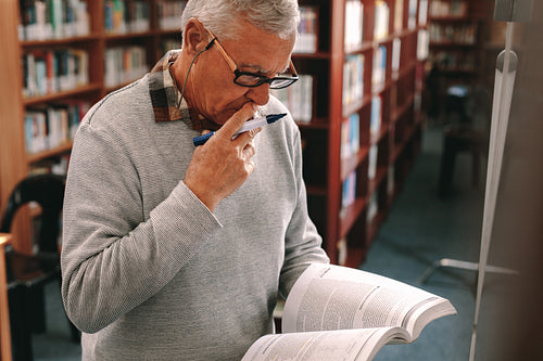 Portrait of a senior man standing in class holding a text book