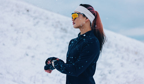 Mountain running brings the runner to a pause as she checks her smartwatch in winter snow