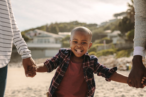 Smiling boy walking with parents on the beach