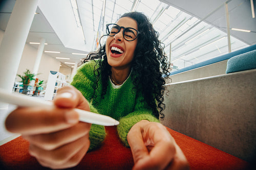 Happy woman creatively drawing on tablet in modern library