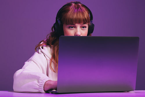 Female gamer playing an online video game on her laptop
