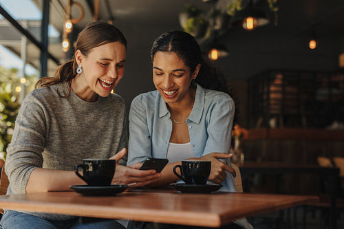 Friends in cafe using phone