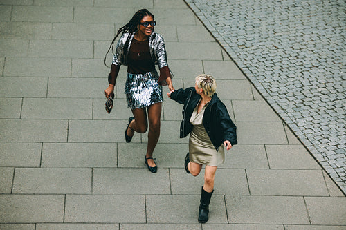 Friends run laughing together through the city outdoors
