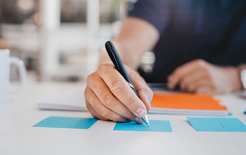 Business man writing on an adhesive note
