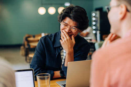 Young male discussing and laughing with colleagues in a casual meeting setting