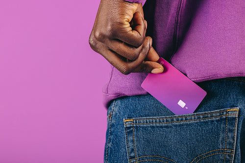 Paying with plastic: Man pulls a purple credit card from his pocket in a studio