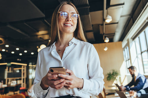 Thoughtful businesswoman holding a smartphone