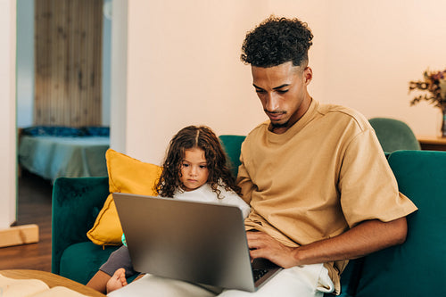 Father and daughter watching an educational video on a laptop