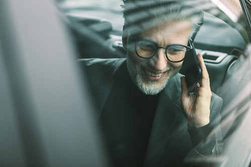 Senior commuter travelling by a taxi and making phone call