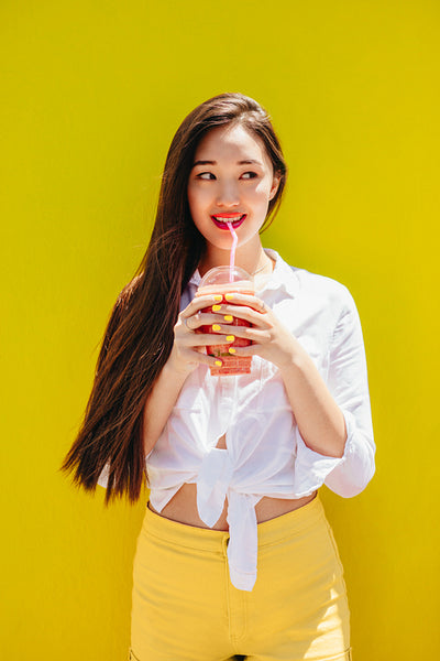 Young asian woman drinking juice outdoors