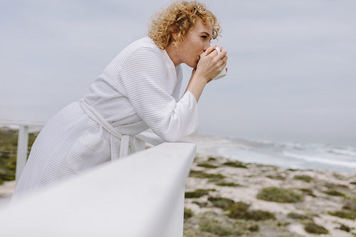 Woman standing in the balcony looking at the sea