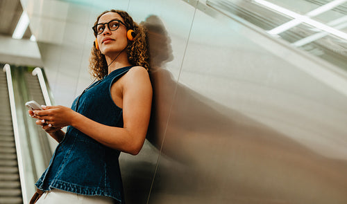 Woman with vintage headphones looks away in urban transit station