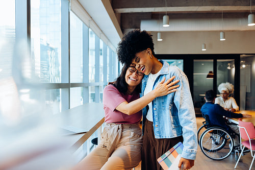 Friends share a hug at modern office