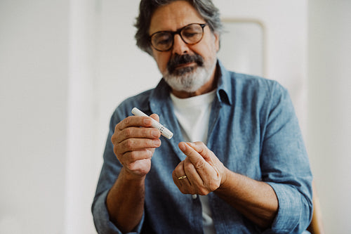 Senior man prepares glucose testing at home