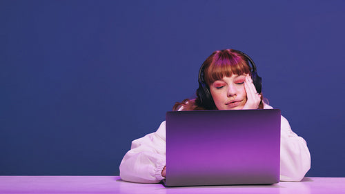 Woman looking at her gaming laptop thoughtfully in a studio