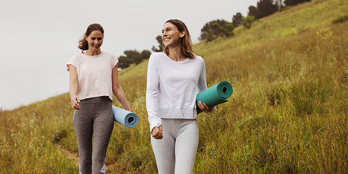 Fitness women walking outdoors holding yoga mats