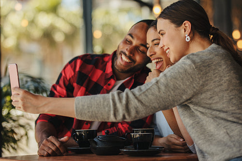 Group of friends taking selfie at coffee shop