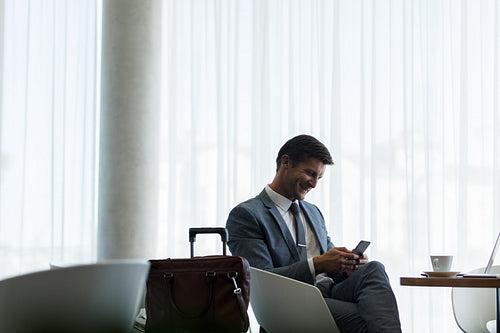 Businessman at airport lounge using mobile phone