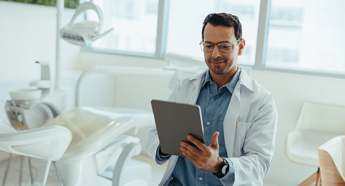 Male dentist using tablet in modern dental clinic