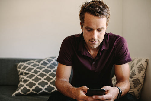Freelancer looking at mobile phone sitting at home