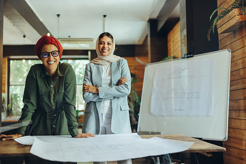 Happy Muslim designers smiling at the camera in an office