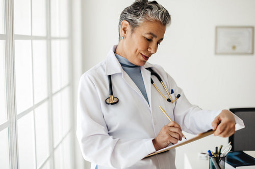 Female doctor writing on a clipboard while standing in an office