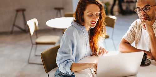 Discussing business in the cafe: Colleagues working with a laptop in a brainstorming meeting