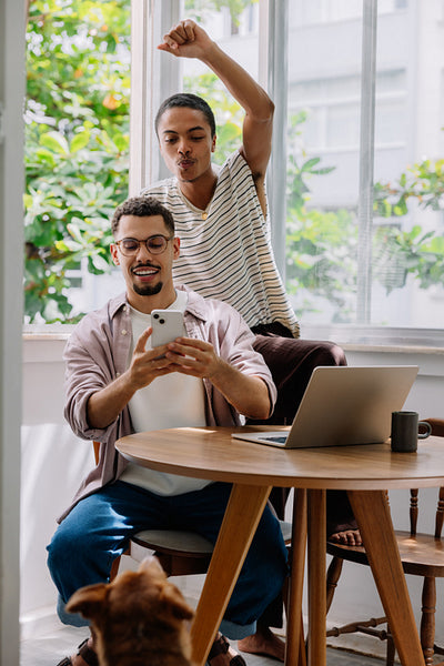 Happy couple enjoying time together at home with a smartphone and laptop