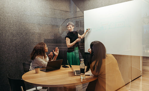 Three women engaged in a collaborative discussion in a small meeting room