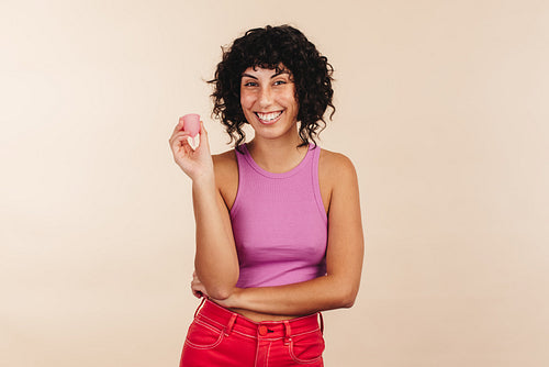 Carefree young woman holding a reusable menstrual cup