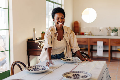 Happy afro woman preparing family breakfast at kitchen table